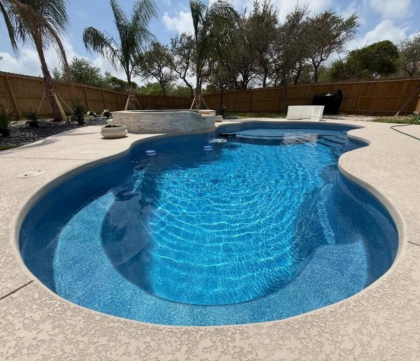 A real Kinetic freeform fiberglass pool with a spillover spa and crystal-clear water
