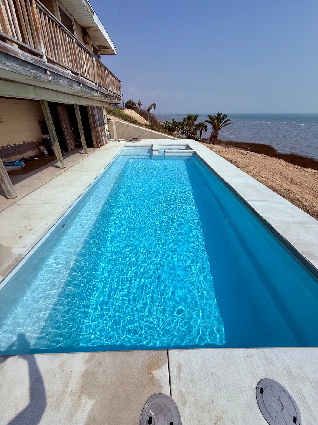 A real Kinetic Pools rectangular fiberglass pool with turquoise water on a Coastal Bend lot overlooking open water