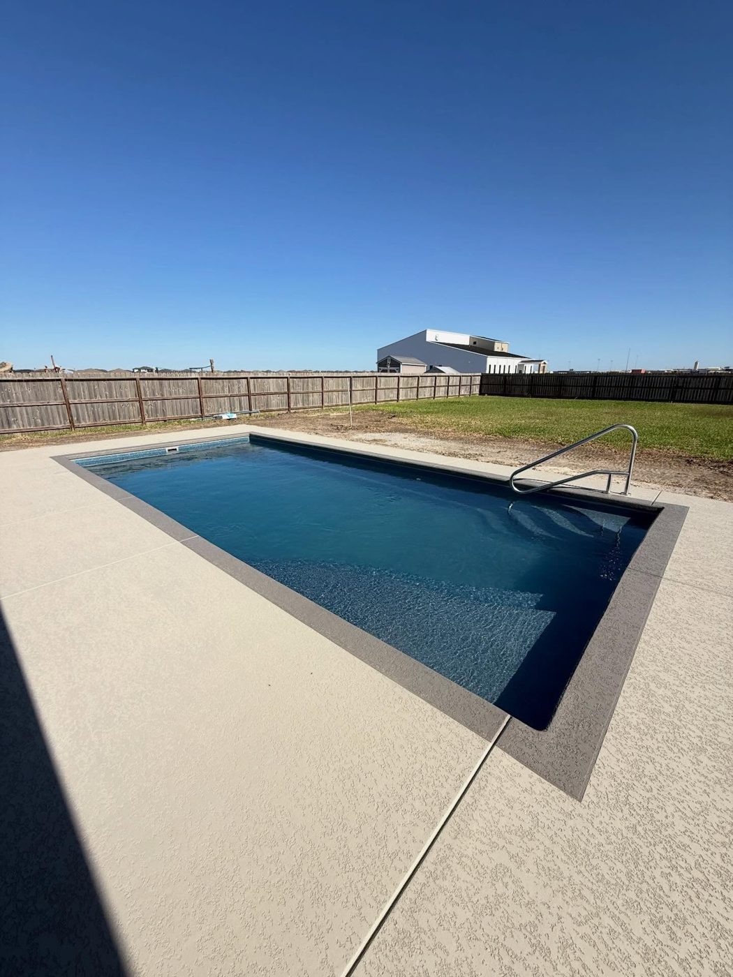 A real Kinetic rectangular fiberglass pool with clean lines beside open coastal water