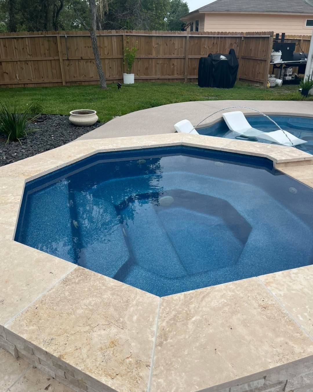 A real Kinetic freeform fiberglass pool set into a travertine paver deck