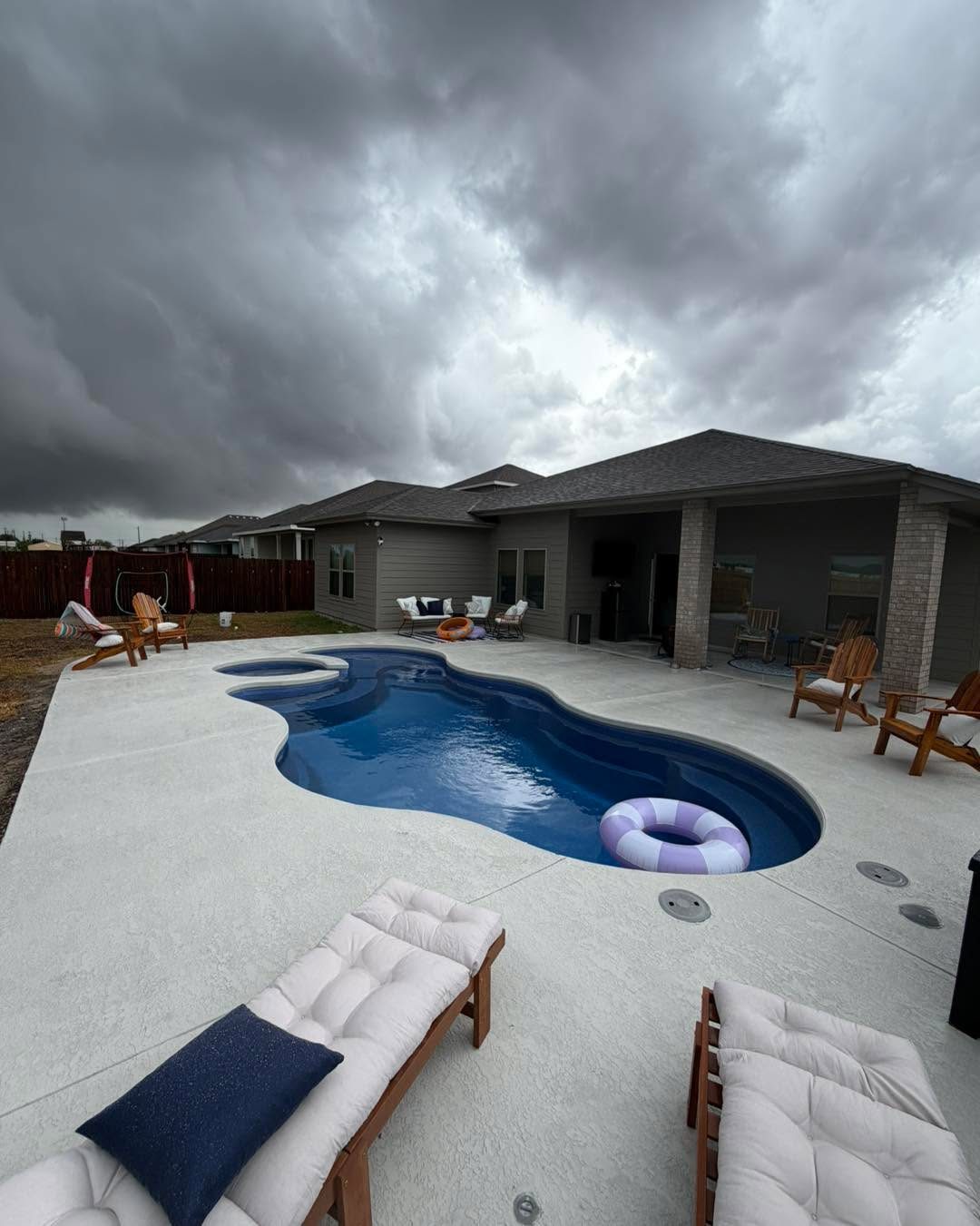 A real Kinetic freeform fiberglass pool with a spa beside a covered patio
